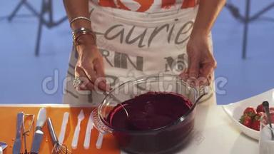 紫罗兰物质从勺子滴到宽边的大玻璃锅里。